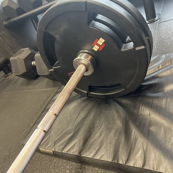 A loaded barbell resting on a rack at the gym