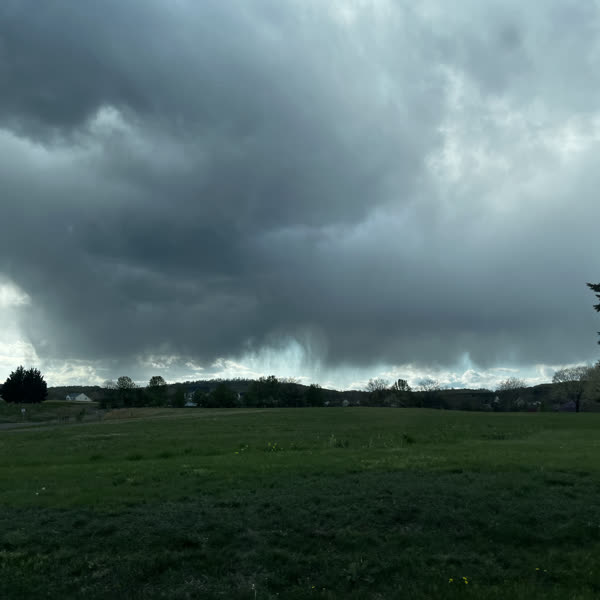Storm clouds breaking over a wide green field