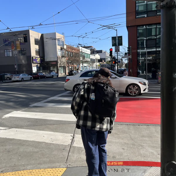 A sunny San Francisco street corner with trolley wires overhead