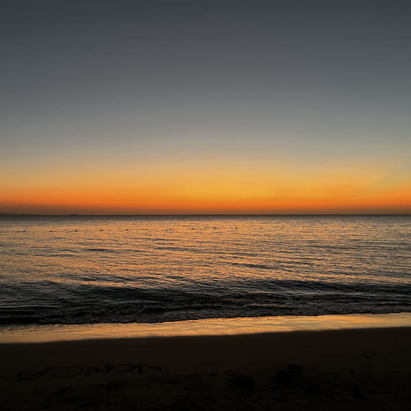 An orange sunset over a calm dark sea